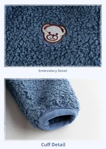 Macro detail of blue fleece jacket showing cute bear embroidery and elastic ribbed cuffs