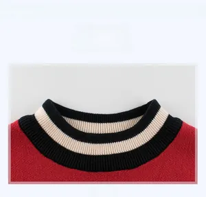 Close-up of the red knitted boy sweater featuring black and white ribbed crew neckline