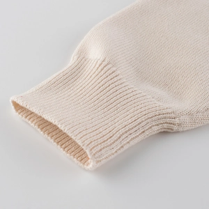 Close-up of boys' cream knit sweater showing detailed ribbed cuffs and high-quality texture