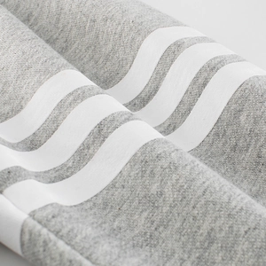 Close-up of gray cotton kids joggers featuring signature four white horizontal stripes