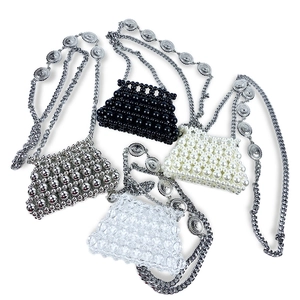 Close-up of four handmade mini woven pearl bags in black white silver and clear colors