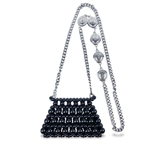 Detail of black beaded mini bag with silver chain strap and vintage metal charms