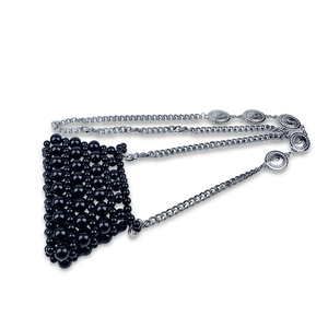Detail of handmade black beaded mini crossbody bag with embossed silver chain strap