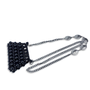 Detail of black beaded mini bag with silver chain and embossed metal charms