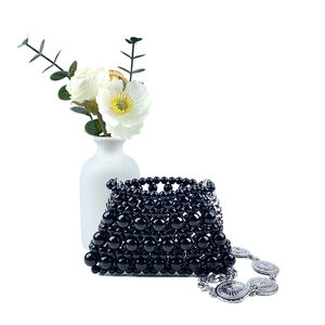 Detailed shot of handmade black beaded mini bag with silver engraved chain strap and floral accent