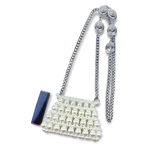 Detail of handmade pearl mini bag with silver chain strap and lipstick size reference