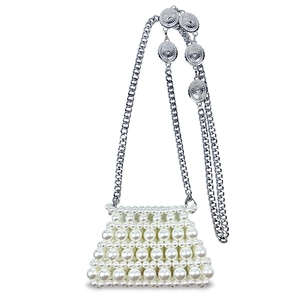 Detail of handmade pearl mini bag featuring silver chain and textured metal disks