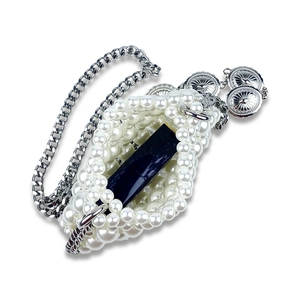 Detail of handmade pearl beaded mini bag with silver chain and metal charms
