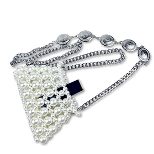 Detail view of handmade pearl mini bag with sun motif silver chain for lipstick