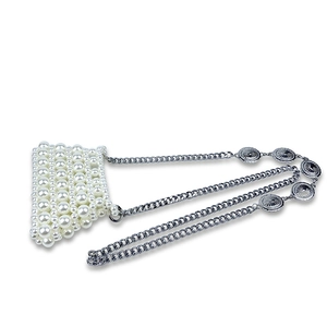 Detail of handmade pearl mini bag with silver chain strap and metal sunburst accents