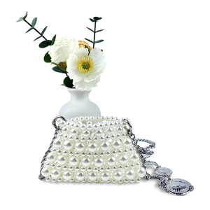 Detail of handmade mini pearl bag with silver chain strap and sunburst metal charm