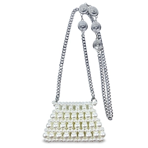 Detail of handmade mini pearl bag with embossed silver charms and metallic chain strap
