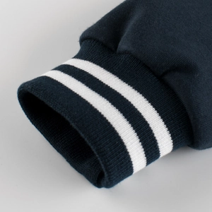 Close-up of navy blue boys' baseball jacket featuring striped ribbed elastic cuffs