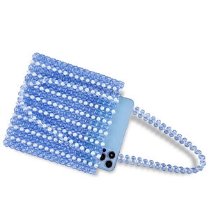 Détail du sac bandoulière perlé montrant des perles bleues et blanches avec un téléphone
