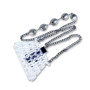 Detail of handmade beaded mini bag featuring clear crystals and engraved metal chain charms