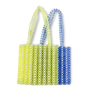 Détail de sacs cabas faits main avec perles acryliques jaunes et bleues et anses tressées