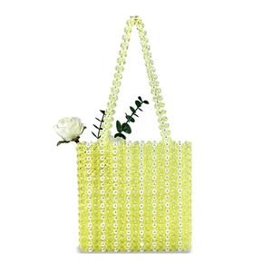 Détail d'un sac perlé fait main avec perles acryliques jaunes et perles blanches