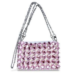Detailed close-up of pink crystal rhinestones and silver chain on woven handbag