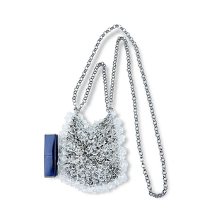 Detailed macro view of clear pleated mini bead bag with silver chain and lipstick for scale