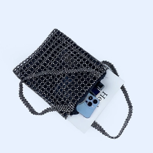 Détail montrant la capacité interne du sac à main en perles noires avec un smartphone