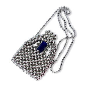 Dettaglio della mini borsa in perline metalliche argento con accento blu e tracolla a catena