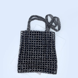 Vue détaillée de la texture perlée gris foncé et du motif tissé ajouré du sac à main