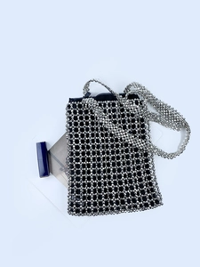 Gros plan du sac bandoulière à perles argentées avec tissage ajouré et doublure noire