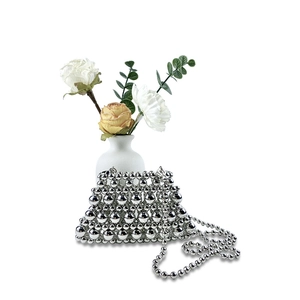 Detail of silver metallic beaded mini bag with pearl chain and elegant floral background