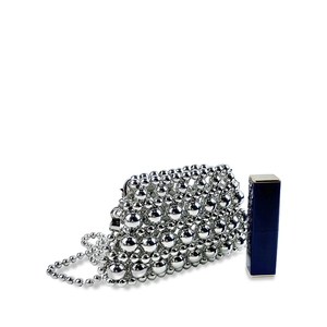 Detail of silver metallic beaded mini bag with pearl chain next to a lipstick for scale