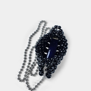 Detail of handmade black beaded mini bag with silver chain and lipstick inside