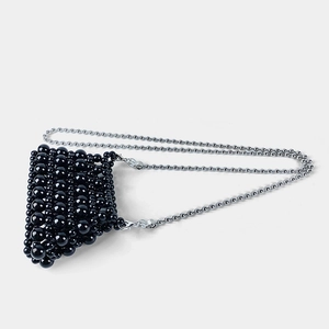 Detail of hand-woven black beaded mini crossbody bag with a slim silver ball chain strap