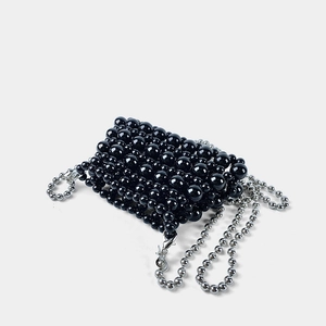 Detail of a mini black beaded handbag featuring shiny pearls and a silver metal chain strap