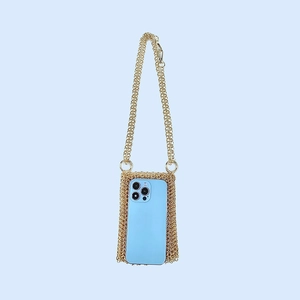 Detailed view of golden handmade metal chainmail crossbody bag holding a smartphone