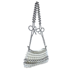 Détail d'un sac à main perlé à la main avec perles argentées et blanches et nœuds élégants