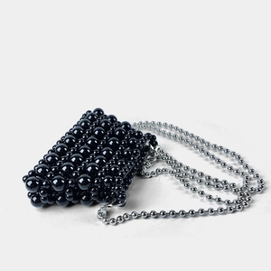 Close-up of hand-woven black beaded mini bag with a polished silver ball chain strap
