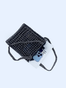 Sac fourre-tout noir fait main en perles montrant sa capacité avec un téléphone