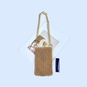 Close-up of golden handmade chainmail phone bag with lipstick and decorative card
