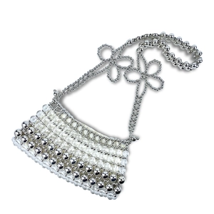Détail de sac à perles avec perles métalliques argentées et anse en forme de fleur