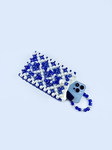 Détail macro du mini sac en perles tressées montrant les perles bleues et le smartphone