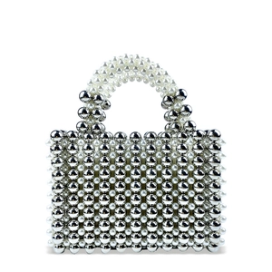Close-up of hand-woven white pearls and silver beads in a checkered texture on a handbag