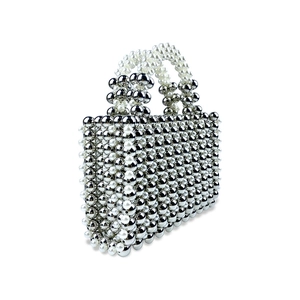 Detailed close-up of woven metallic silver and faux pearl beads on a luxury evening bag