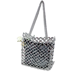 Detail view of a silver beaded tote bag with a white fabric rose and black inner pouch