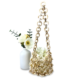 Detail der gewebten Beuteltasche mit cremefarbenen Acryl- und Goldmetallringen