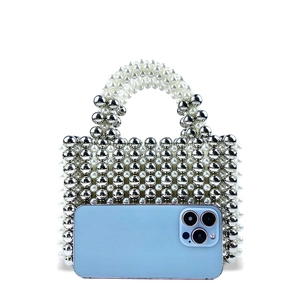 Handmade beaded bag with silver and pearl beads shown next to a smartphone for size scale