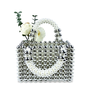 Detail of silver beaded handbag with pearls, featuring white roses on a white background