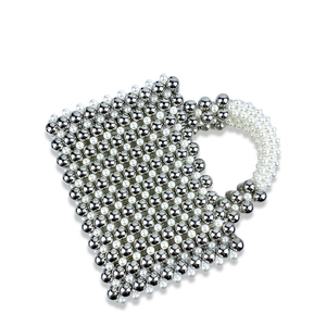 Detailed close-up of handcrafted woven bead handbag with white pearls and silver metal beads