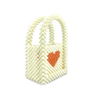 Detail shot of mini handmade beaded purse with red heart pattern on white acrylic beads
