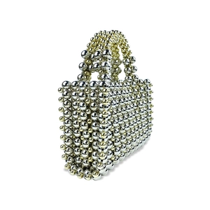 Detail of silver beaded mini tote bag featuring woven metallic spheres and dual handles