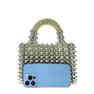 Detailed view of luxury beaded handbag showing metallic gold beads next to a smartphone