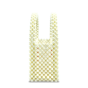Macro detail showing white faux pearl weave texture on a mini handmade square handbag